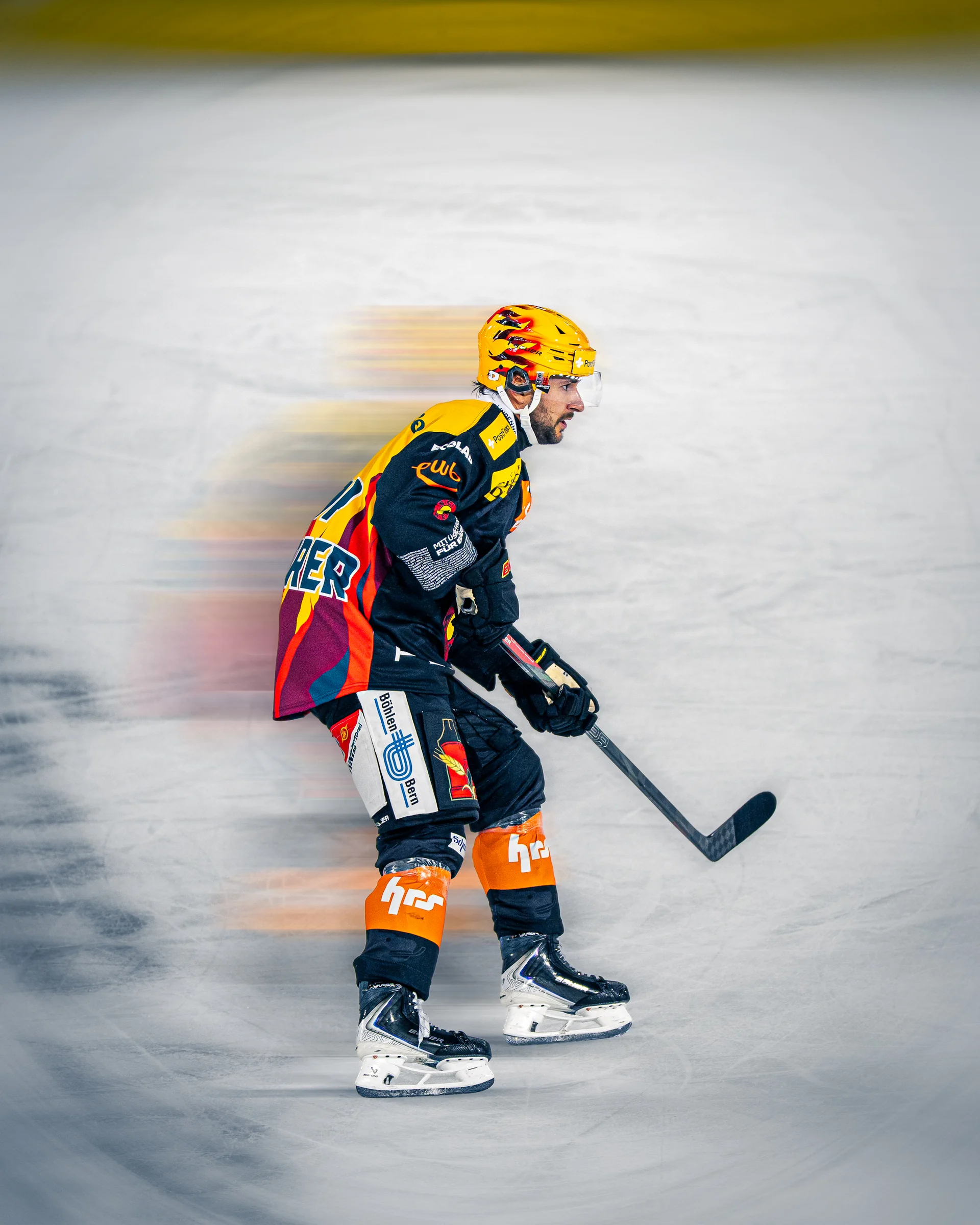 SC-Bern-Spieler mit gelbem Helm vor verwischtem Eis