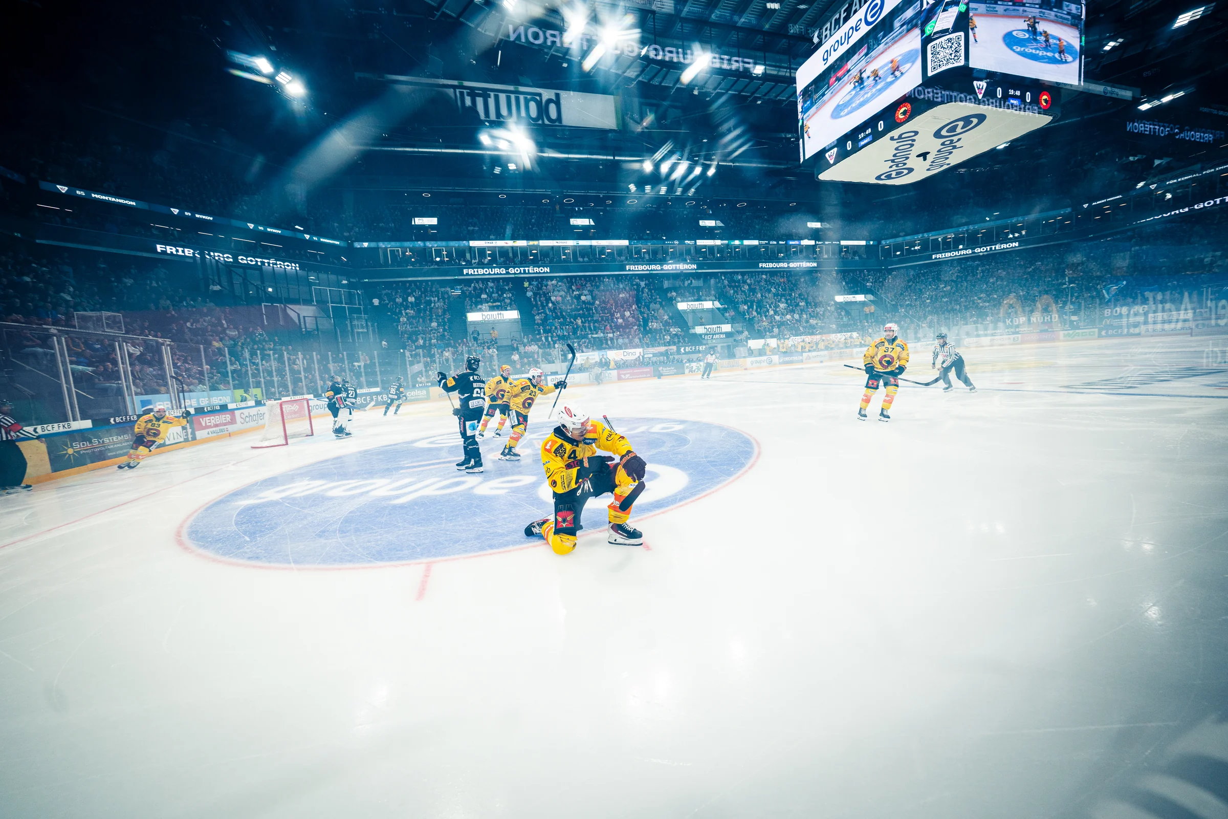 Blick auf das beleuchtete Eisfeld mit SC-Bern-Spielern in gelben Trikots