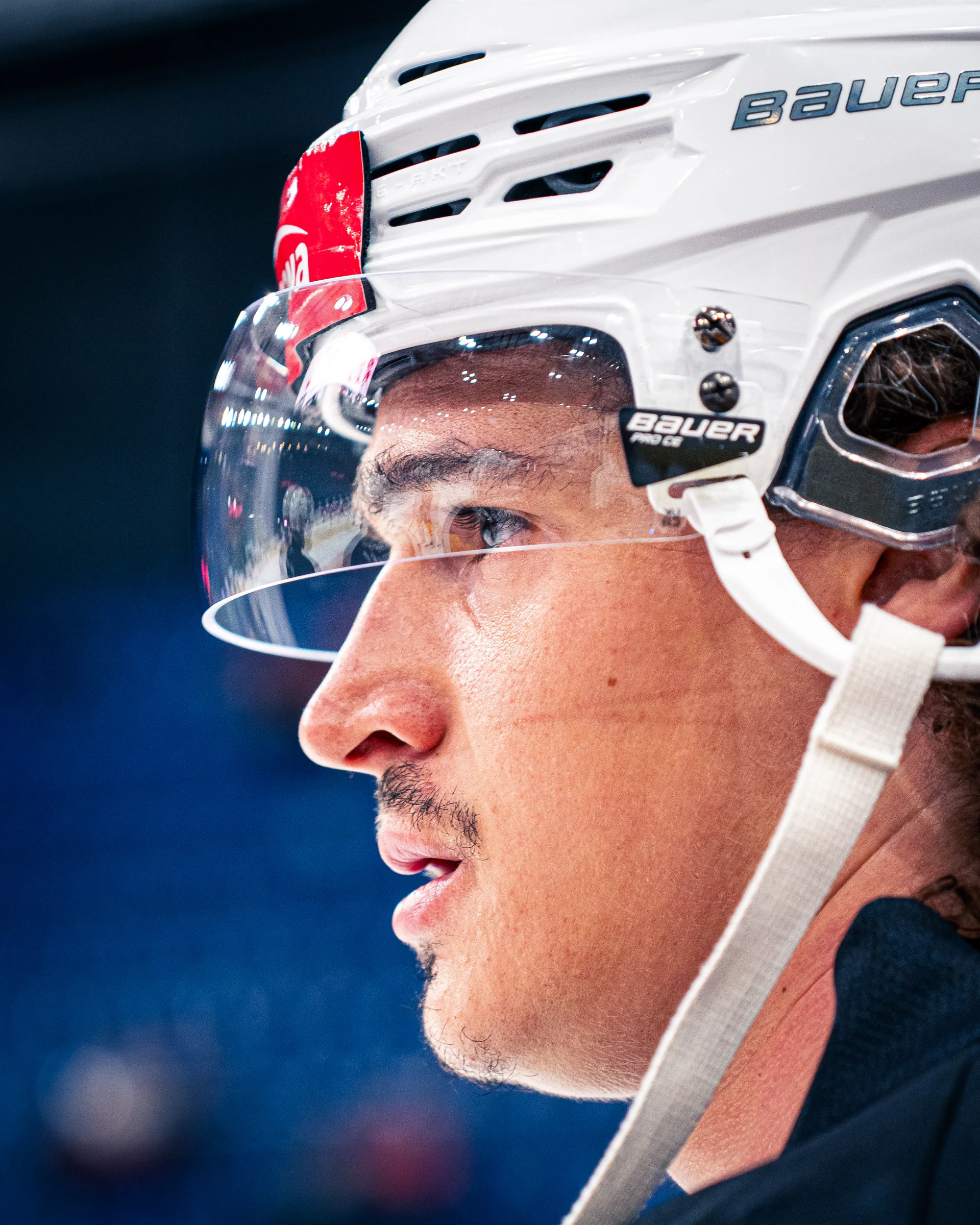 Nahaufnahme eines Eishockeyspielers mit weissem Helm im Profil