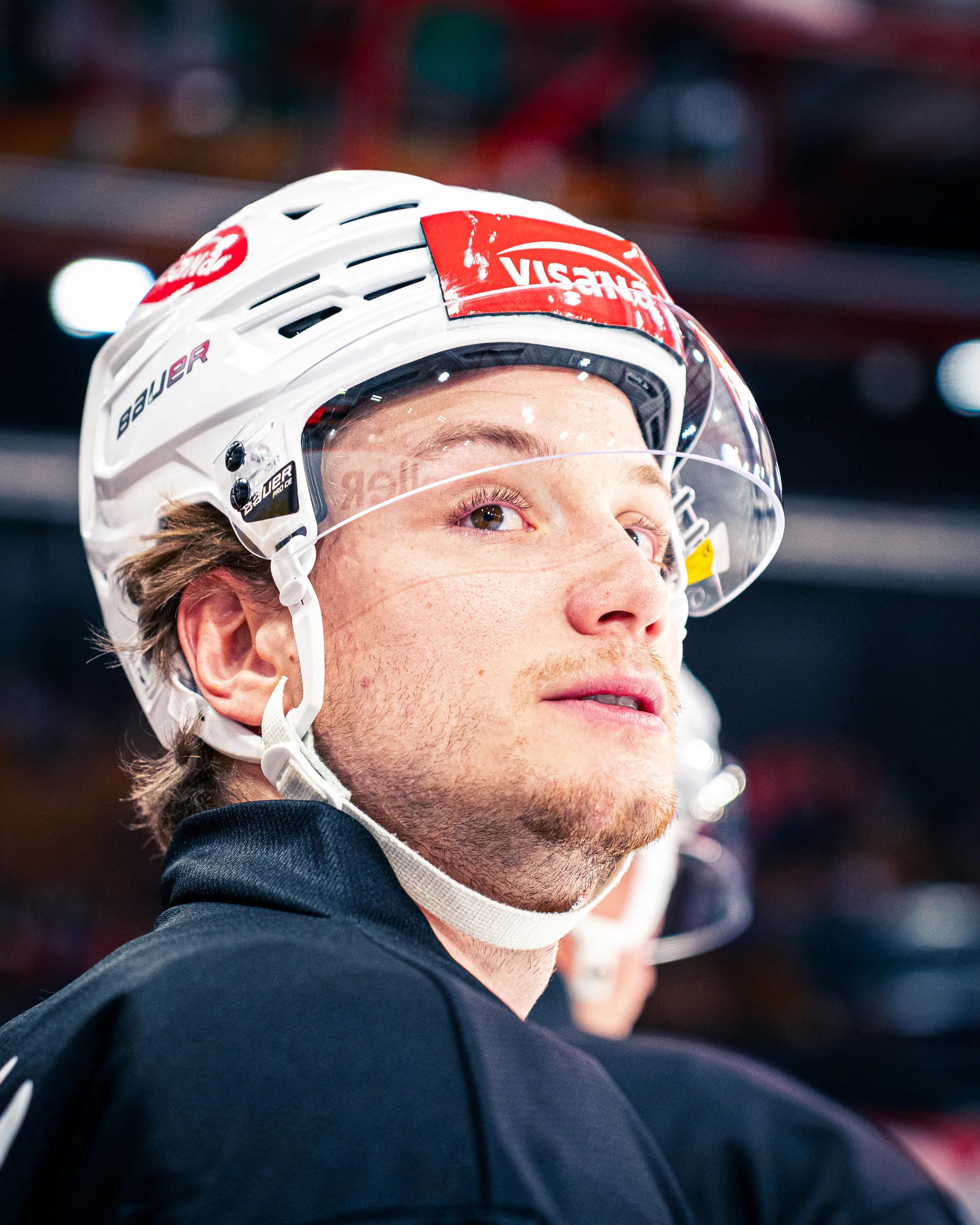Porträt eines Eishockeyspielers mit weissem Helm und schwarzem Oberteil