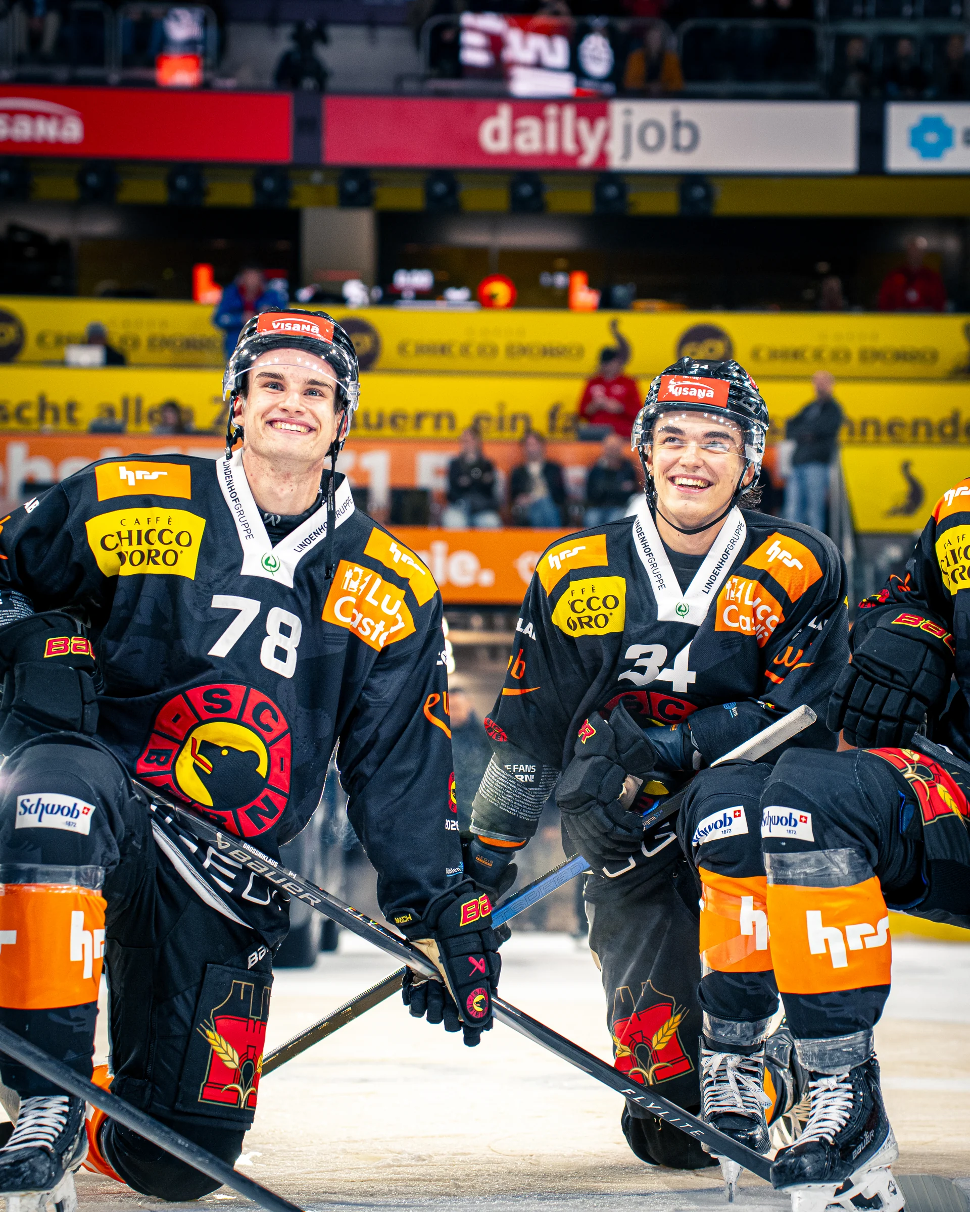 Zwei lächelnde SC-Bern-Spieler mit den Nummern 78 und 31 knien auf dem Eis