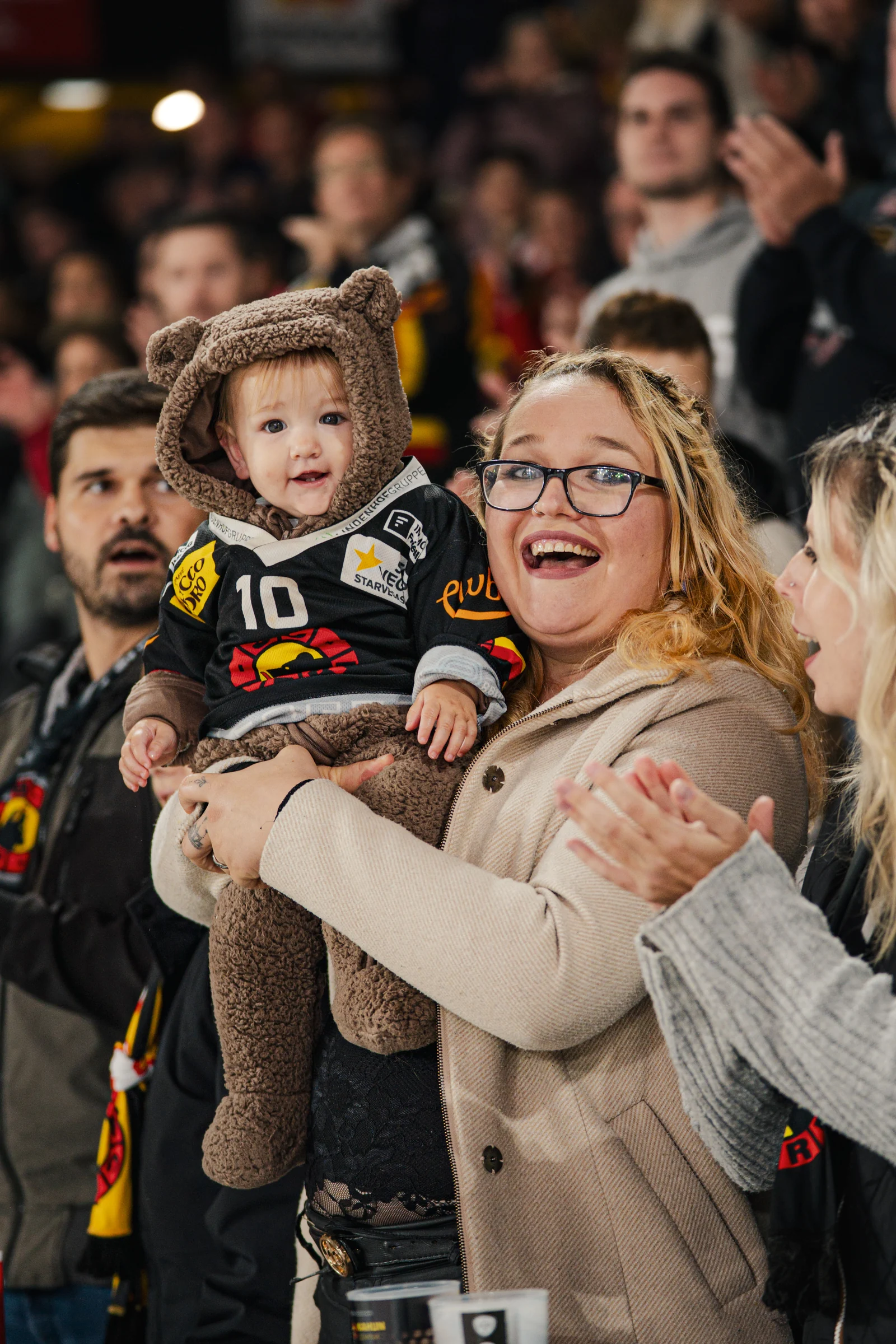Ein Kind mit Gehörschutz auf dem Arm einer Zuschauerin in der Arena