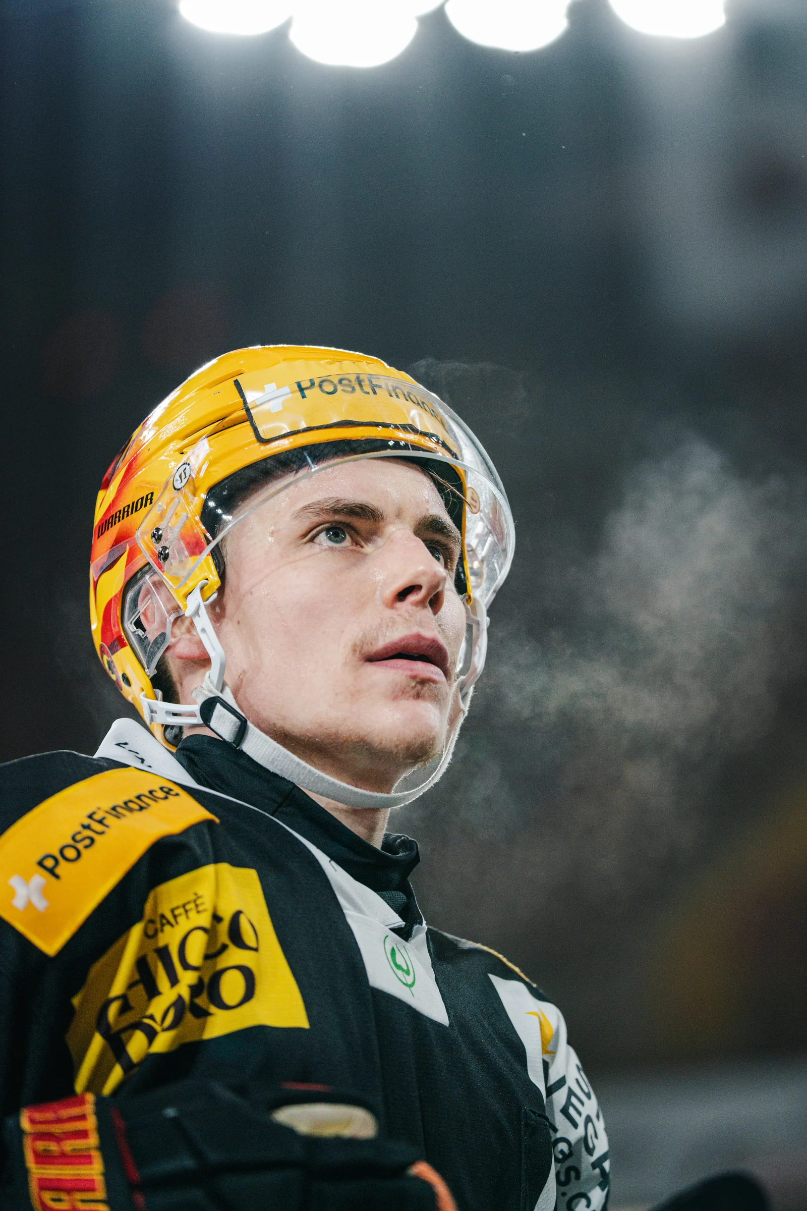 Porträt eines SC-Bern-Spielers mit gelbem Helm unter den Hallenlichtern
