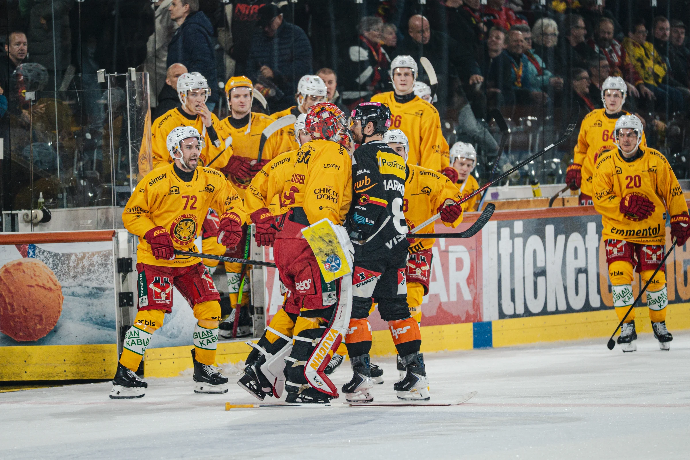 Eishockeyspieler in Rot-Gelb und Schwarz-Gelb vor der Zuschauertribüne